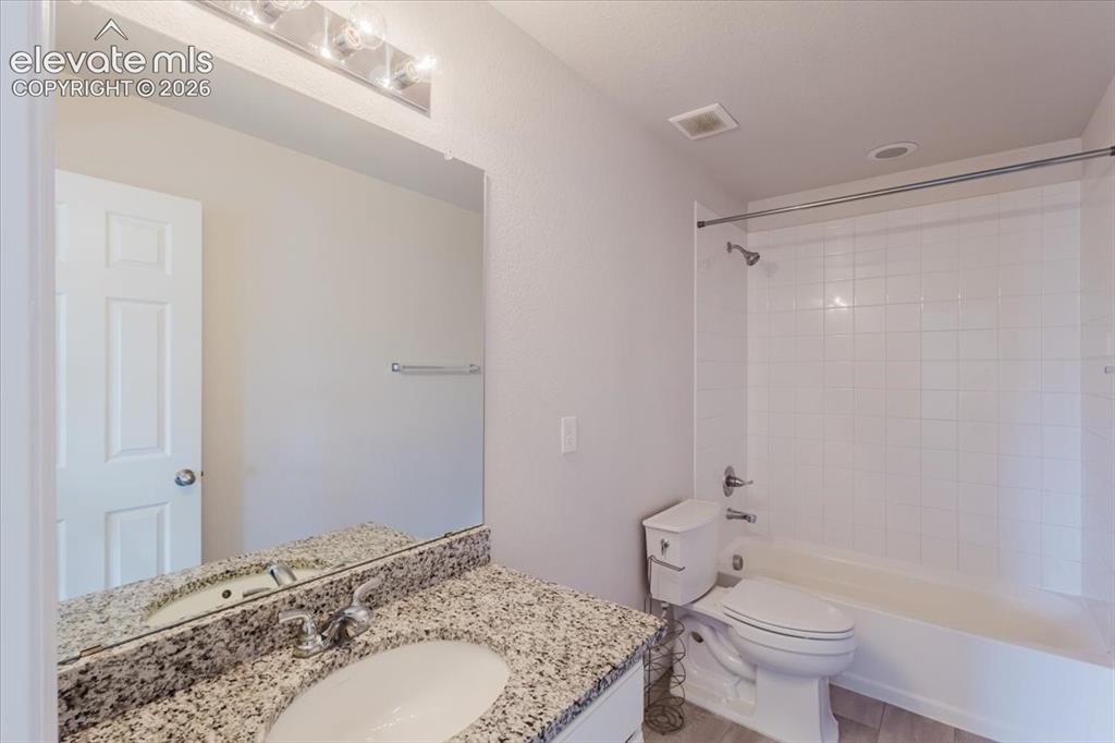 Image 33 of 50: Bathroom featuring a white subway-tiled shower-tub combination, a toilet, a