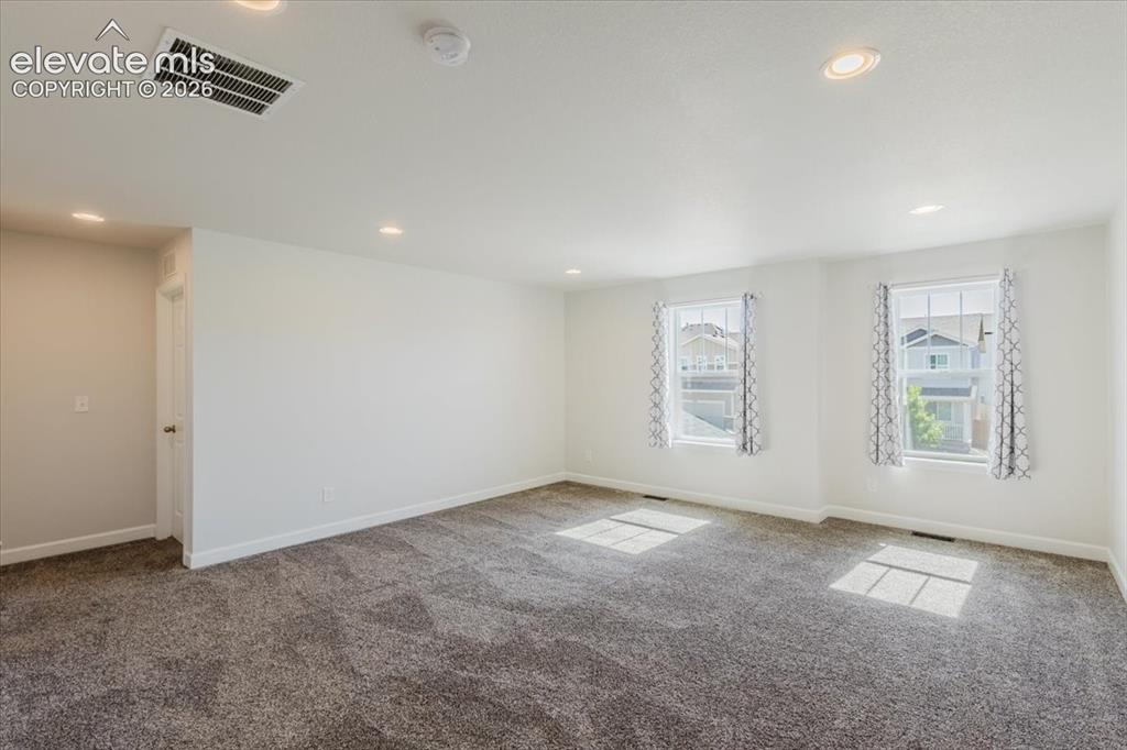 Image 36 of 50: Spacious room featuring neutral carpet flooring, recessed lighting, and two