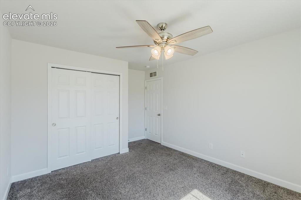 Image 39 of 50: Neutral-toned room with plush carpeting, featuring a ceiling fan with integ