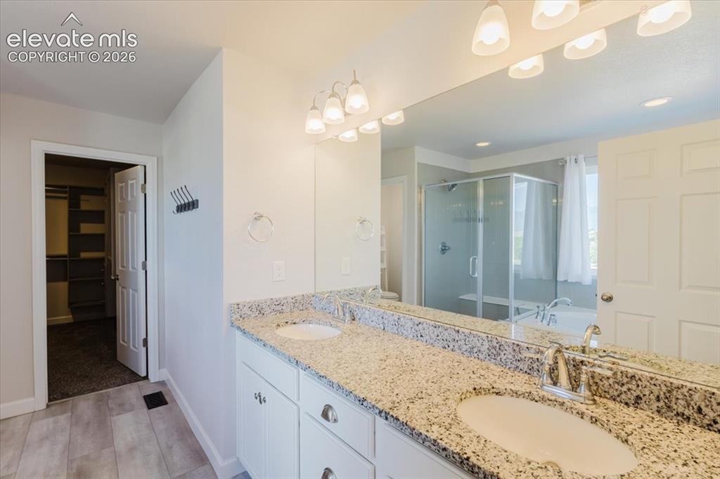Image 43 of 50: Double vanity with undermount sinks, speckled countertop, and chrome fixtur