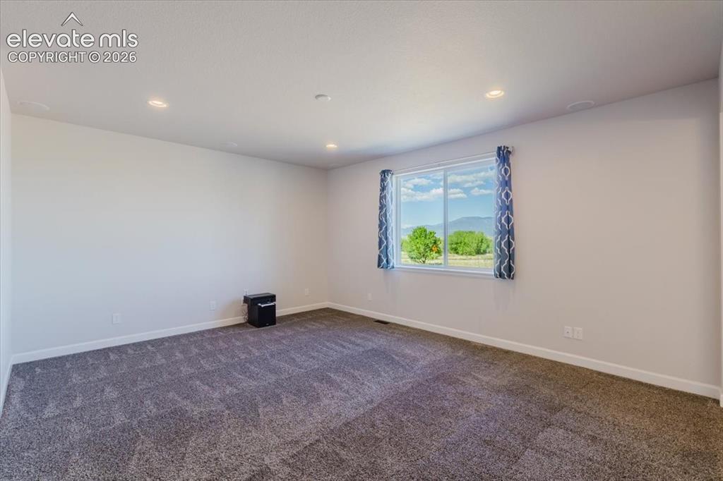 Image 49 of 50: Spacious room with gray patterned carpet, light gray walls, and recessed li
