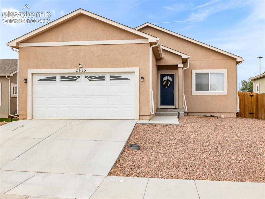 Caption: Stucco exterior with a peaked roofline, an attached two-car garage, a dark blue entry door, and a gr