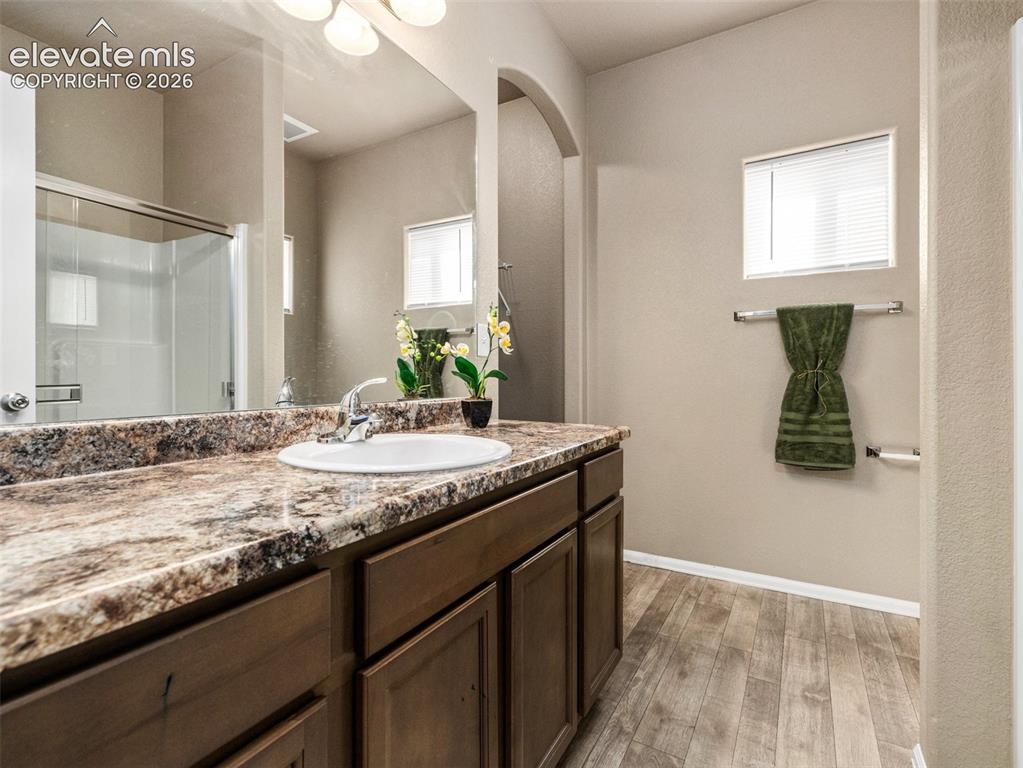 Image 13 of 24: Spacious vanity with a large mirror, integrated sink, and granite-patterned