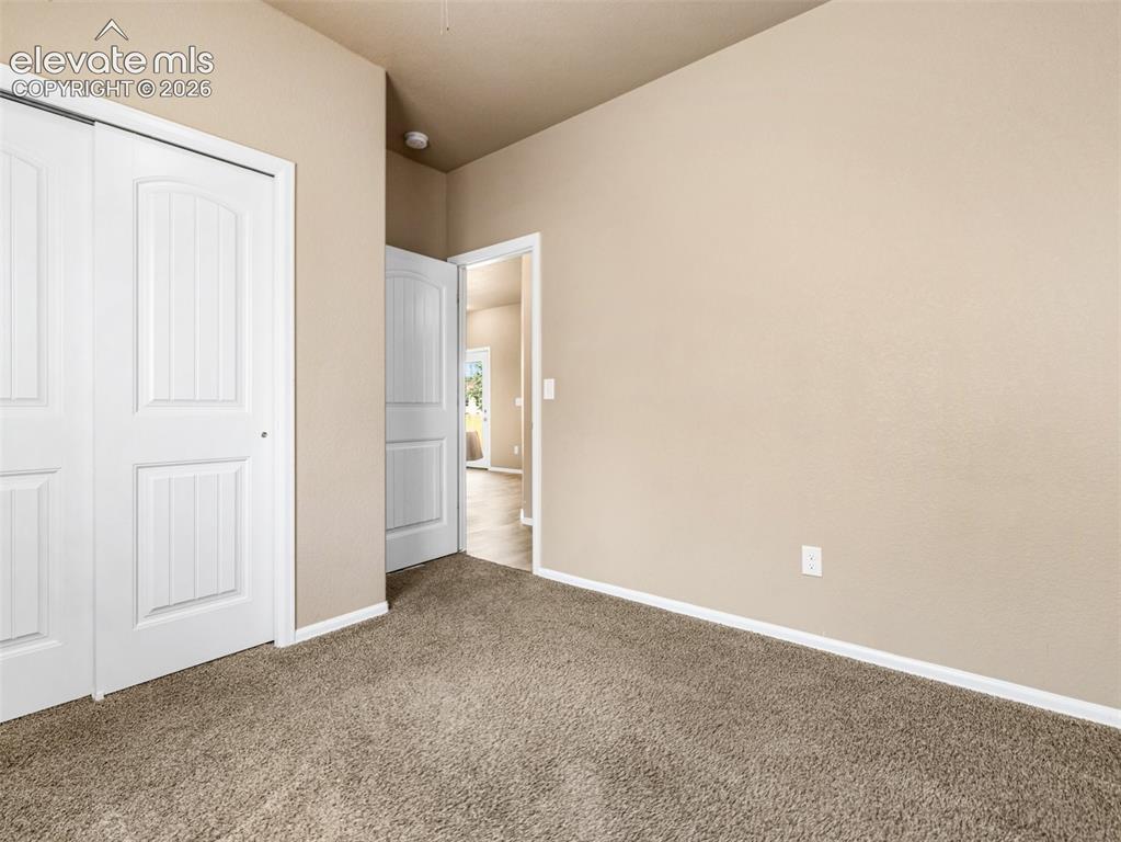 Image 18 of 24: Bright carpeted bedroom with neutral wall finishes, dual closet storage inc