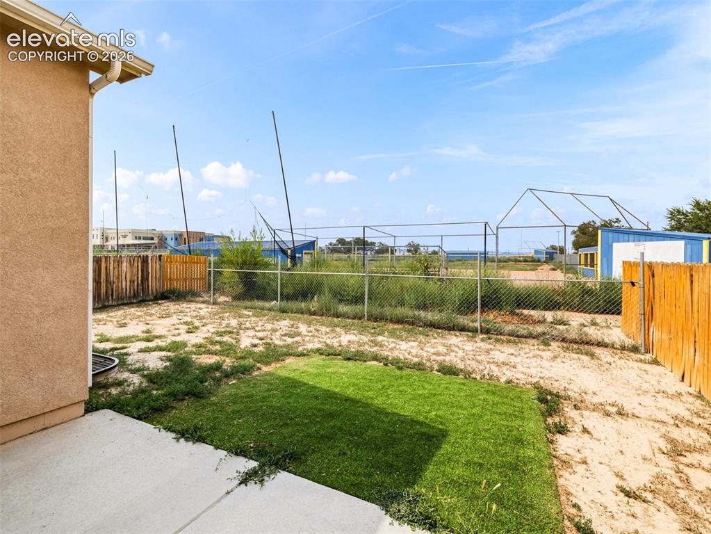 Image 23 of 24: Rear patio with concrete slab and a combination of wood and chain-link fenc