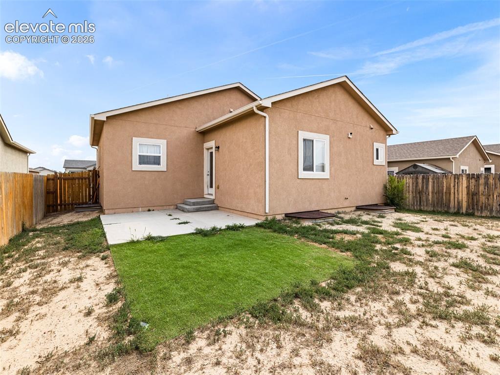 Image 24 of 24: Rear exterior with a concrete patio, stucco siding, and a partial wood fenc