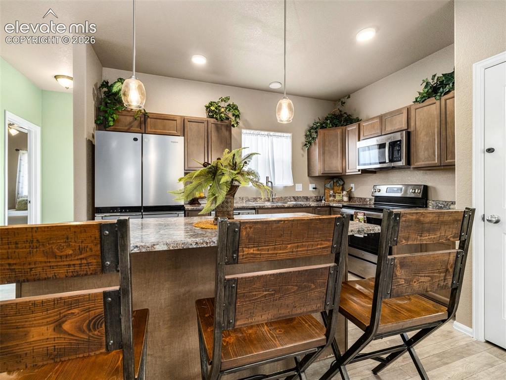 Image 6 of 24: Kitchen featuring wood-finish cabinetry, stainless steel appliances, speckl