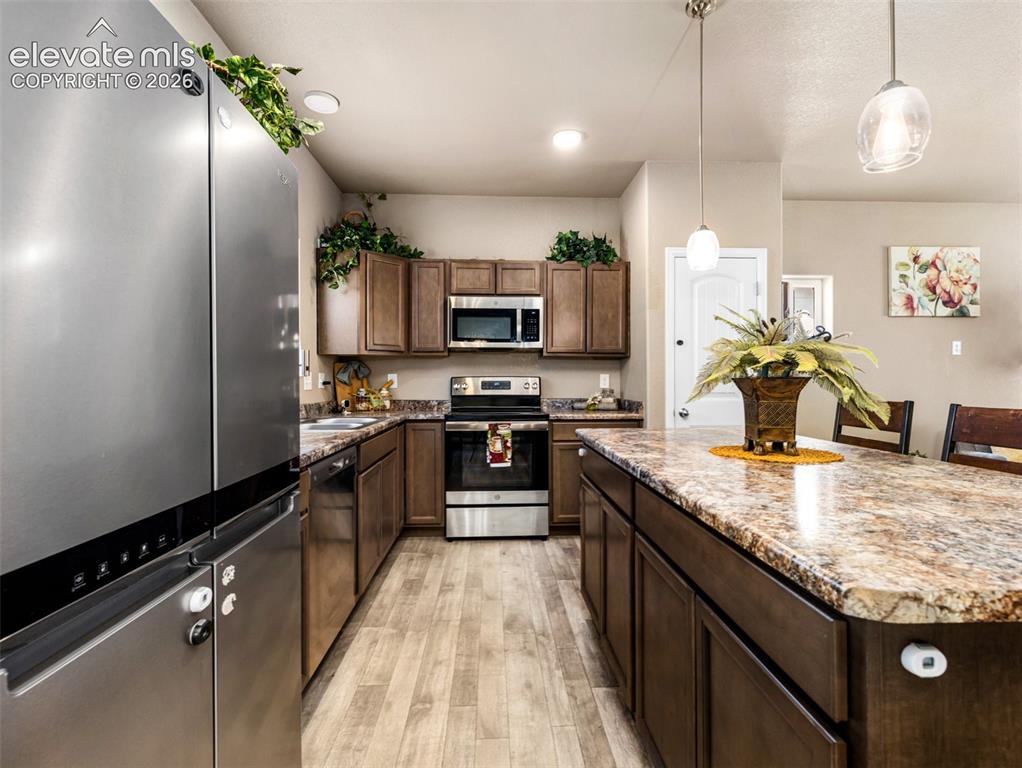 Image 7 of 24: Kitchen featuring wood-finish flooring, dark wood cabinetry, stainless stee