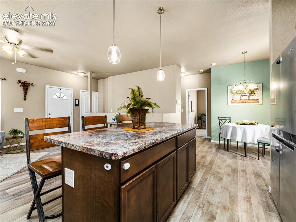 Image 8 of 24: Open-concept kitchen and dining area featuring a dark wood cabinetry island