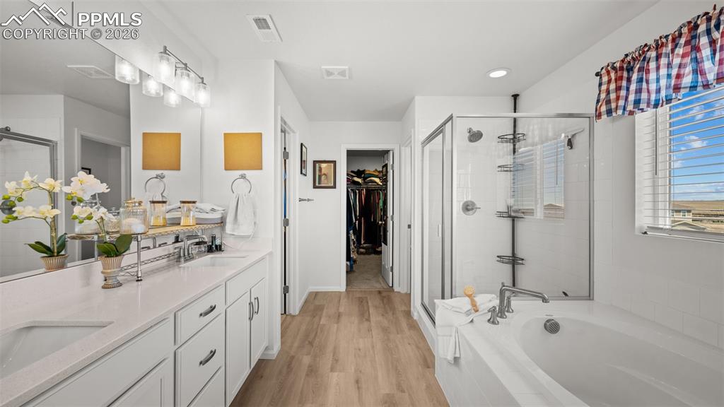 Image 19 of 46: Primary bathroom with quartz counters, large soaking tub, walk in shower an