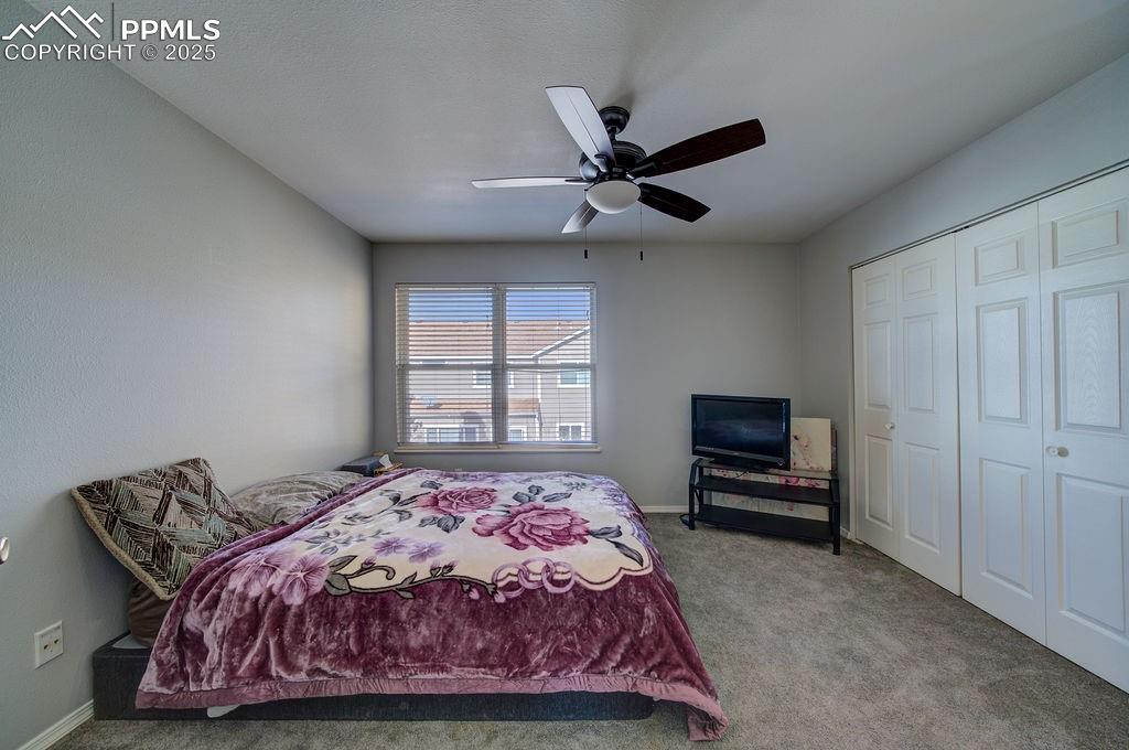 Image 27 of 37: Upper level Bedroom #2 has neutral carpet, a lighted ceiling fan, a closet,