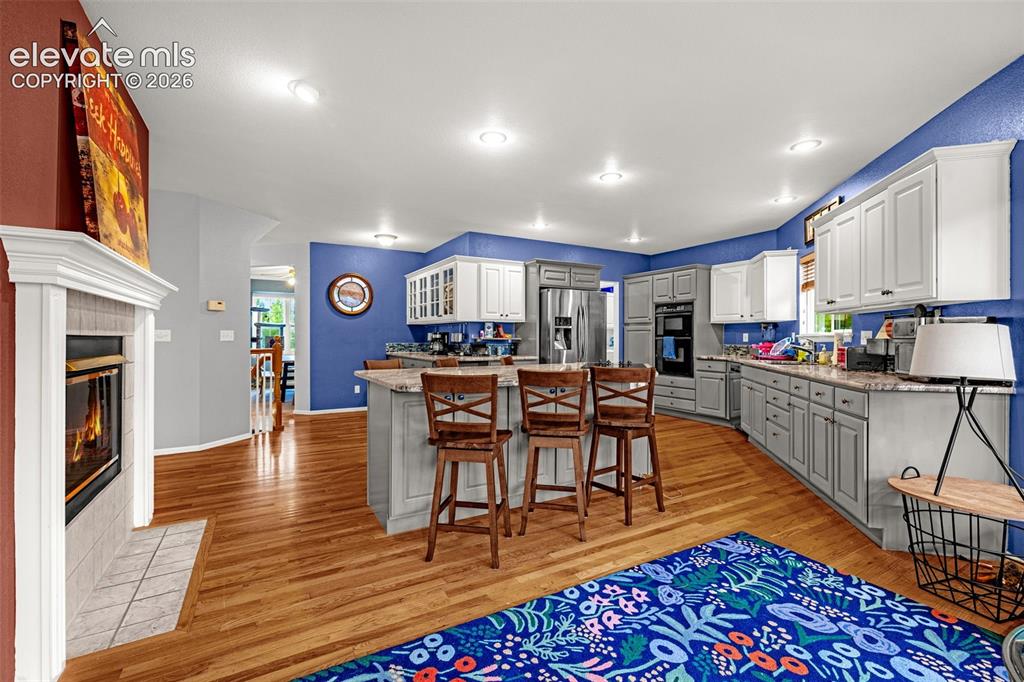 Image 11 of 50: Open-concept living space featuring wood-finish flooring, a contemporary fi