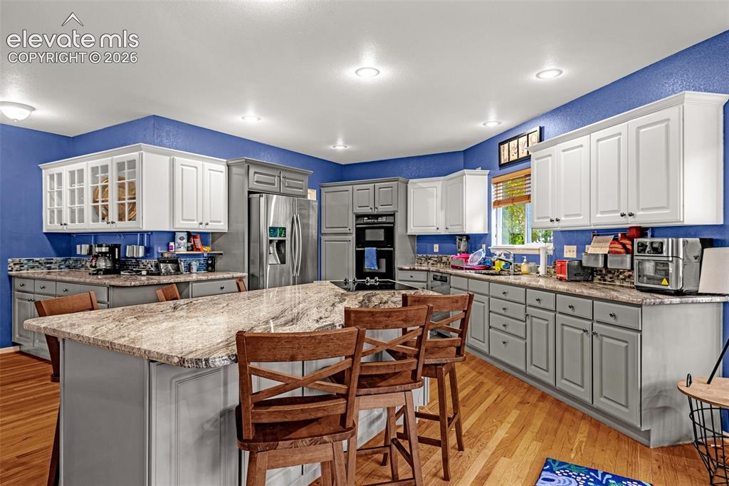 Image 12 of 50: Kitchen featuring a large island with stone countertop, stainless steel app