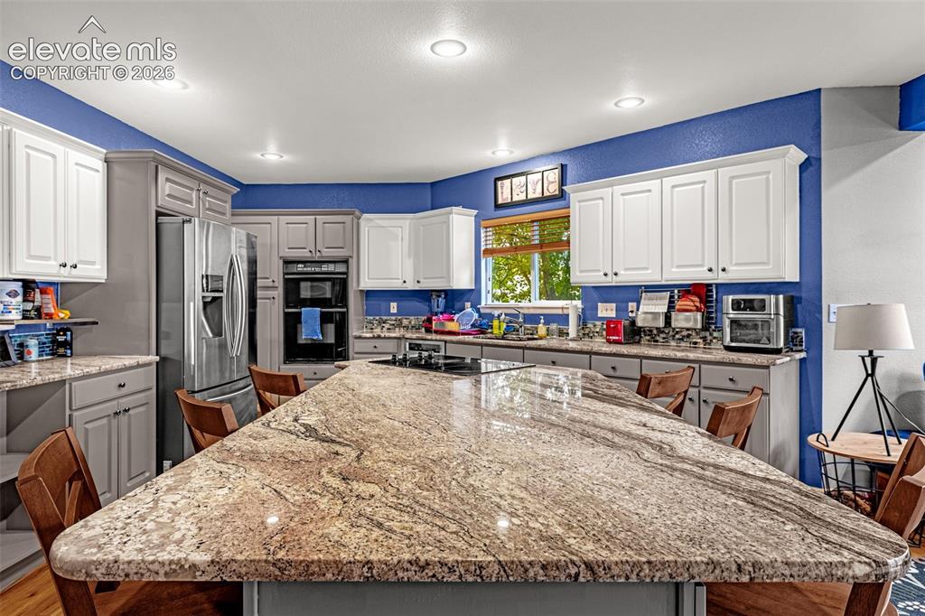 Image 13 of 50: Spacious kitchen featuring a large island with a stone surface, recessed li