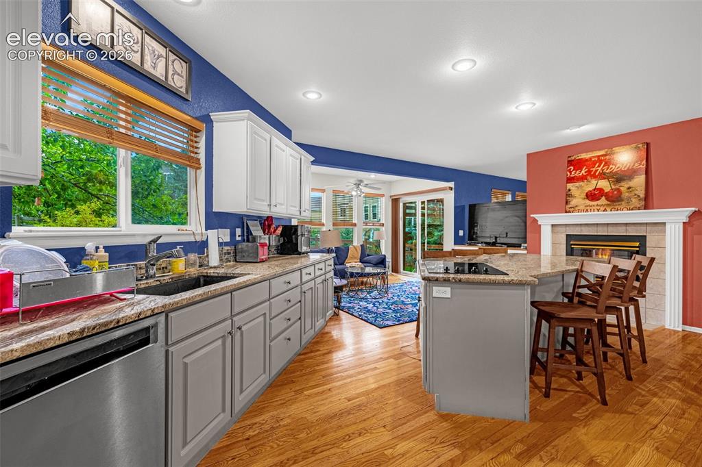 Image 14 of 50: Kitchen featuring wood-finish flooring, white upper cabinetry, gray lower c