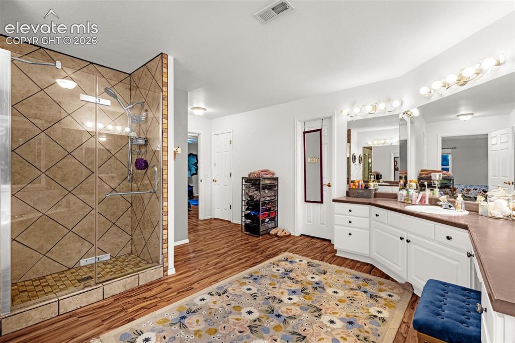 Image 21 of 50: Glass-enclosed shower with diamond-patterned wall tile, wood-finish floorin