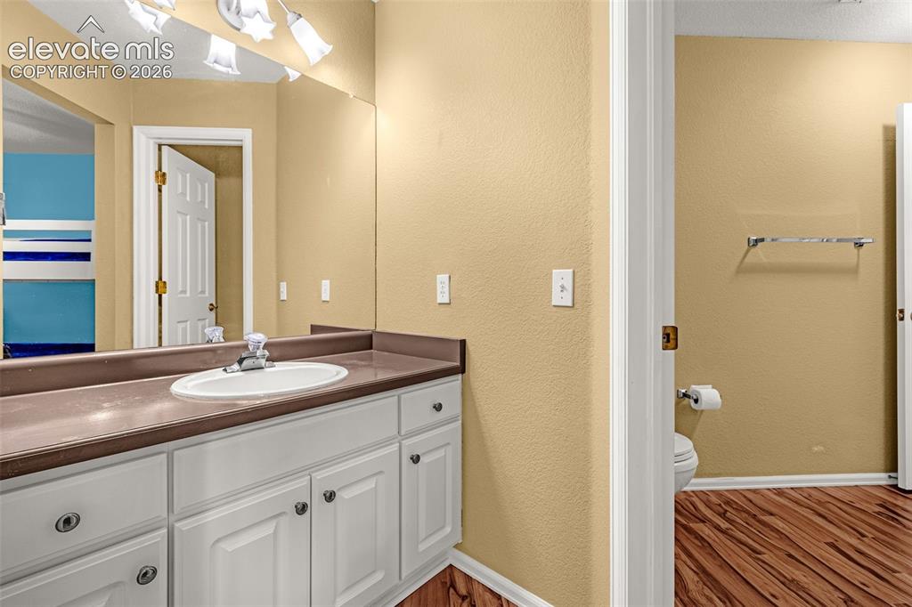 Image 29 of 50: White vanity cabinetry with circular hardware, a contrasting countertop, an