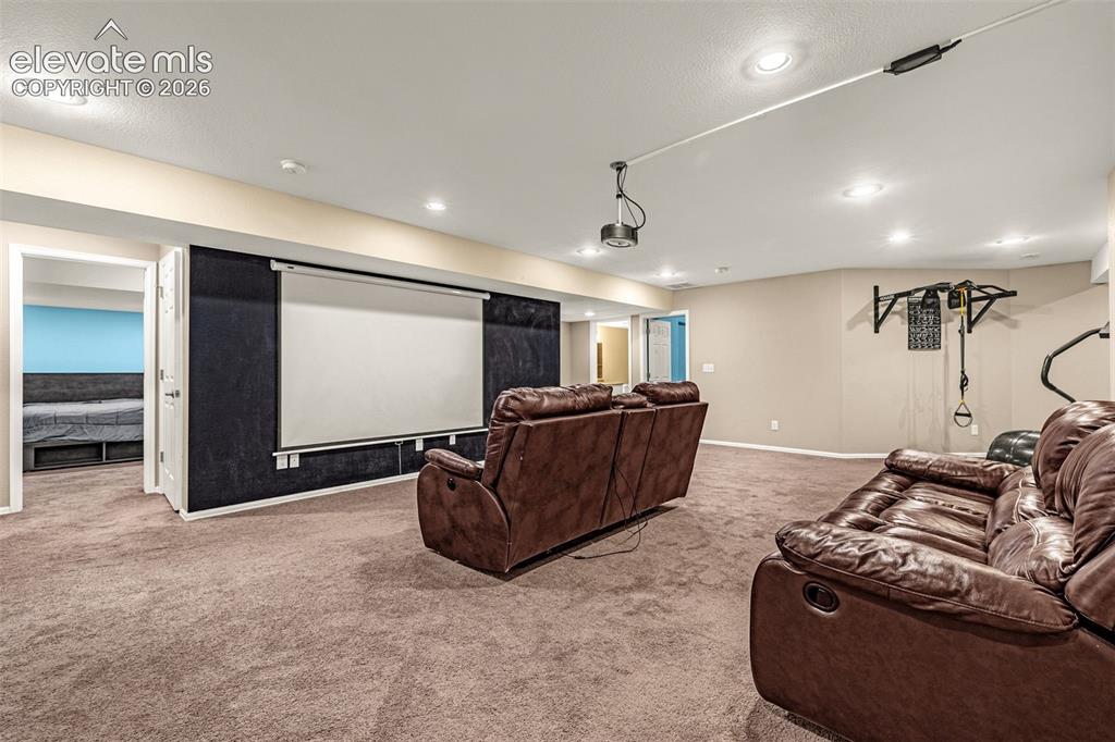Image 34 of 50: Recessed lighting, projector screen, wall-mounted projector, and carpeted f