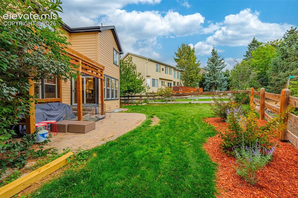 Image 37 of 50: Expansive backyard featuring a manicured lawn, wood fencing, and landscaped