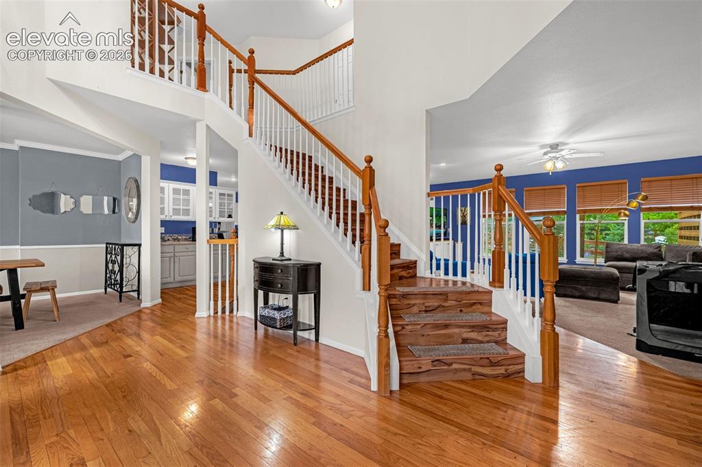 Image 4 of 50: Hardwood flooring, wood-finish staircase with white risers, and a two-story
