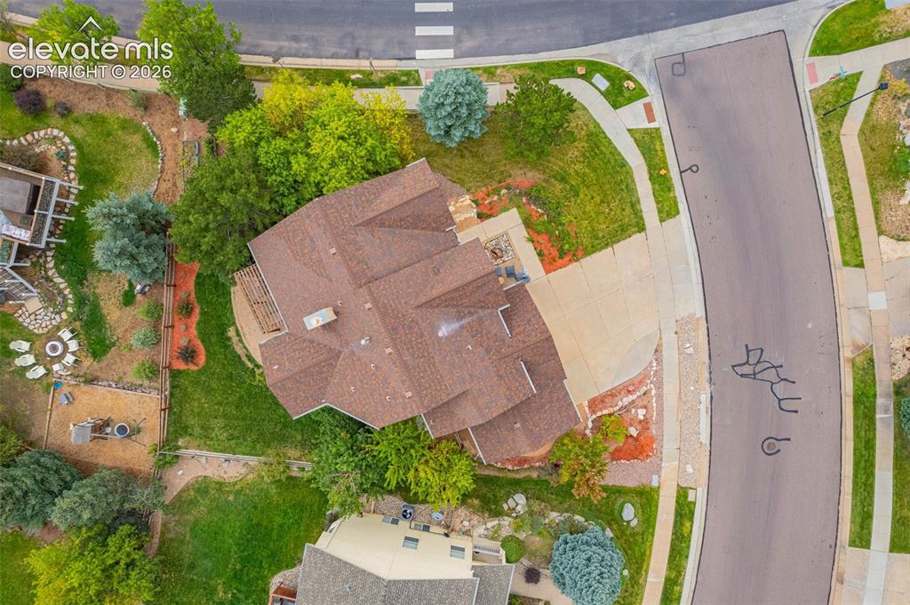 Image 40 of 50: L-shaped asphalt driveway, brown shingle roof, mature landscaping, paved si