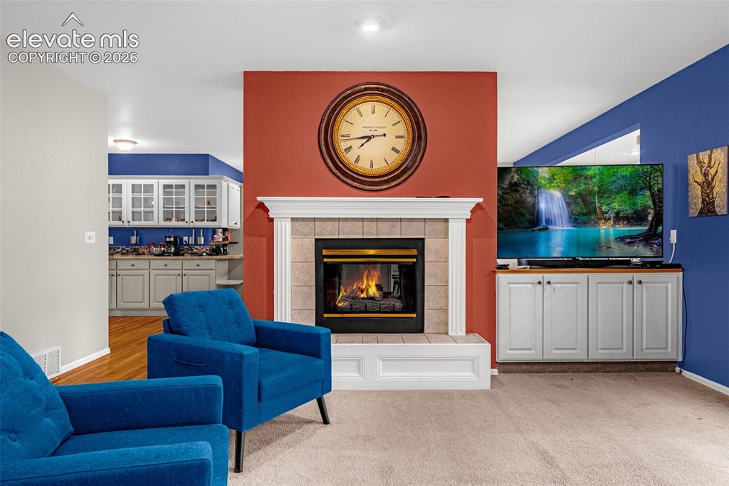 Image 8 of 50: Fireplace with a tile surround and white mantel, flanked by built-in cabine