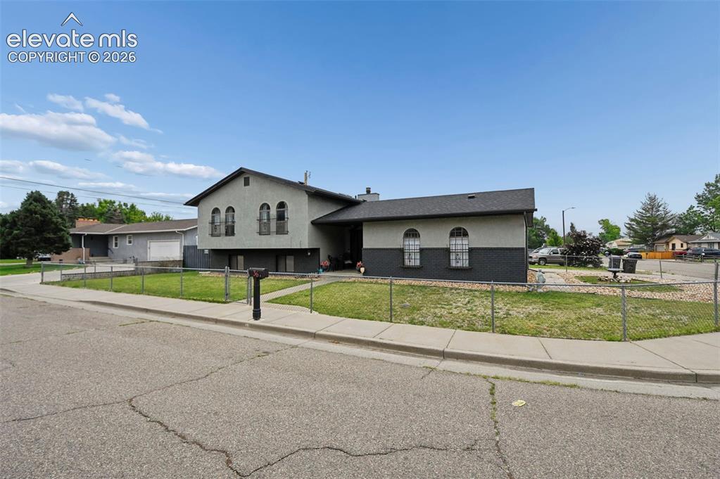 Image 16 of 20: Two-tone exterior with arched windows, chain-link perimeter fencing, and a