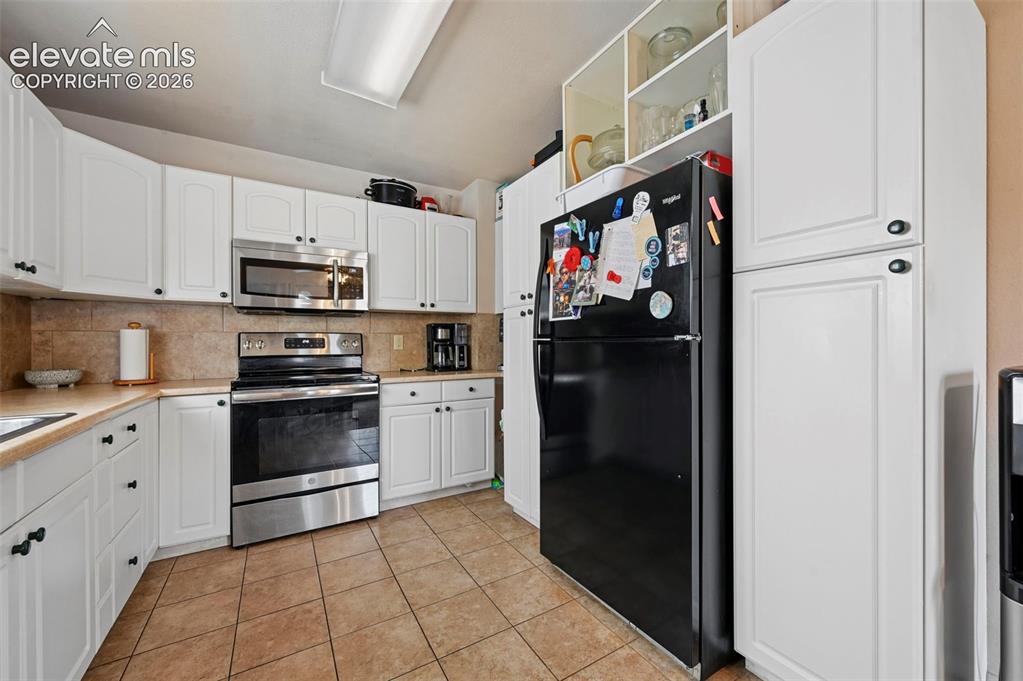 Image 4 of 20: Kitchen featuring white cabinetry, tile flooring, stone-finish countertops,