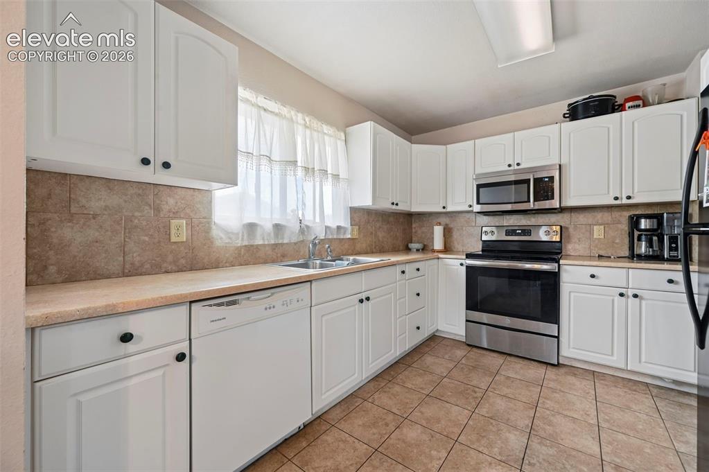 Image 5 of 20: Kitchen featuring white cabinetry, stone-look tile flooring, and a coordina