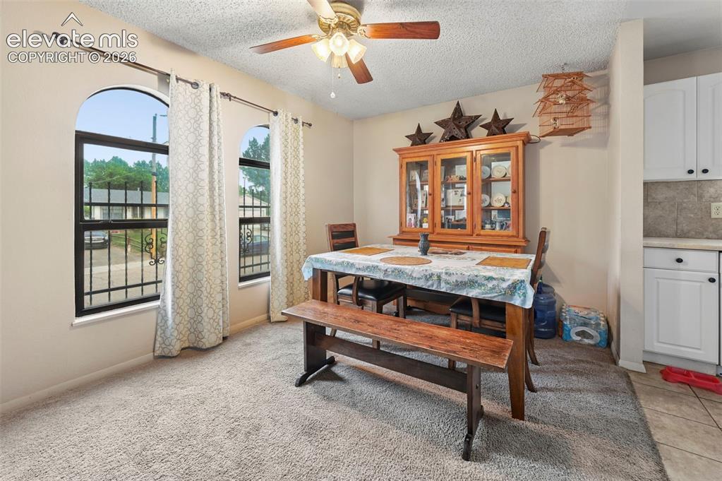 Image 7 of 20: Carpeted dining area featuring two arched windows with security bars, a cei
