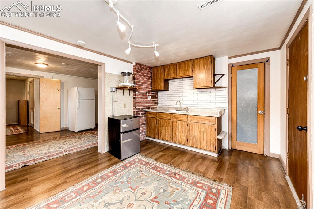 Image 23 of 34: Kitchen with dark wood-type flooring, light countertops, a sink, and freest