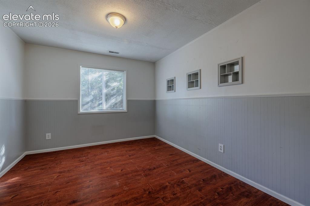 Image 11 of 36: Wood-finish flooring, white trim, and a window with a white frame