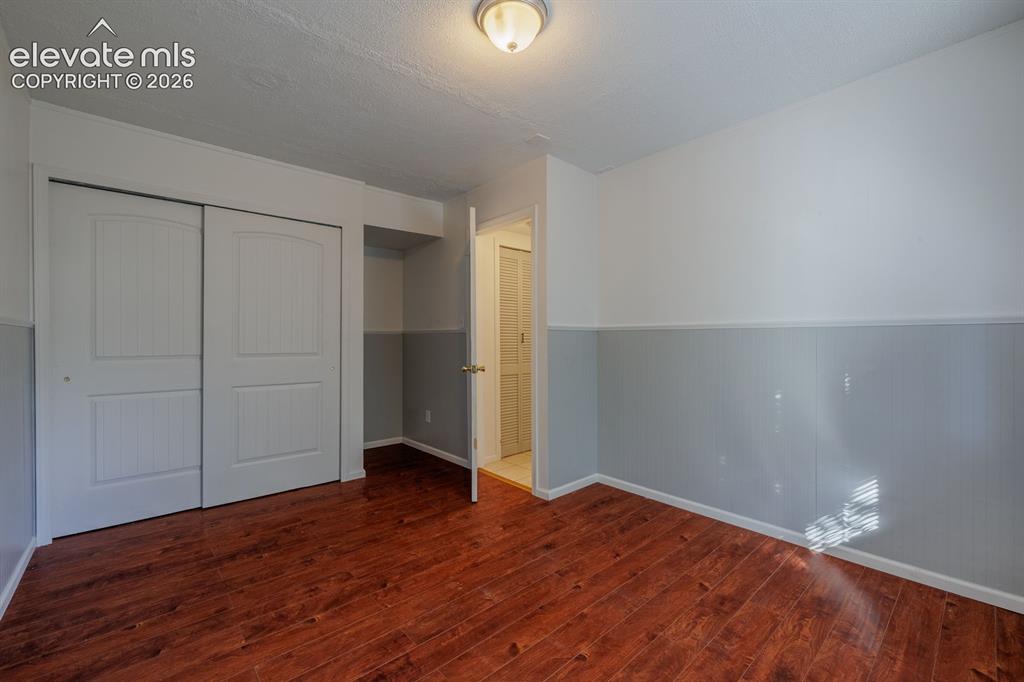 Image 12 of 36: Wood-finish flooring, half-wall wainscoting, and a ceiling-mounted light fi