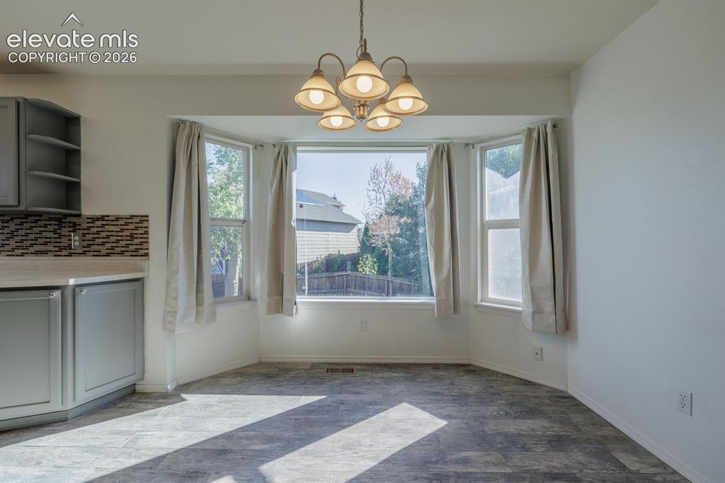 Image 16 of 36: Built-in cabinetry with open shelving, mosaic tile backsplash, bay window,