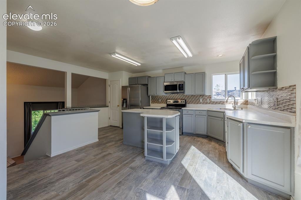 Image 17 of 36: Kitchen featuring wood-finish flooring, gray cabinetry, stainless steel app