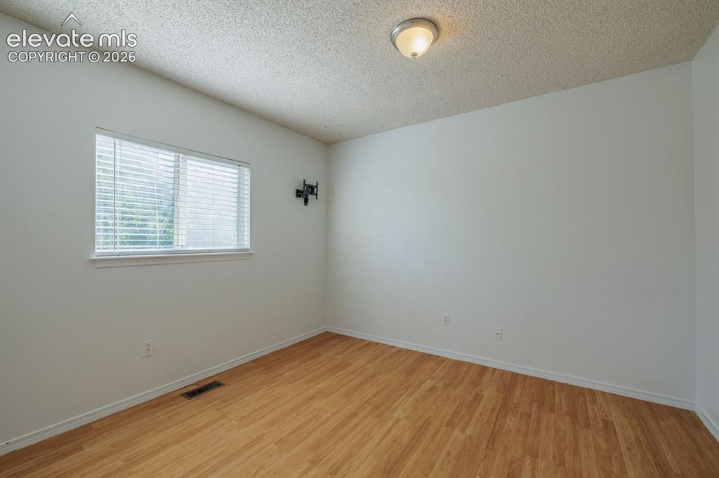 Image 18 of 36: Wood-finish flooring, white walls, and a ceiling-mounted light fixture