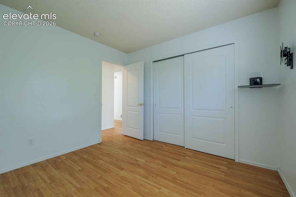Image 21 of 36: Wood-finish flooring, white walls, and a white sliding closet door