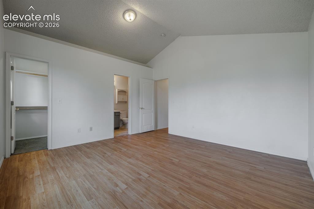 Image 25 of 36: Vaulted ceiling room featuring wood-finish flooring, a flush-mount ceiling 
