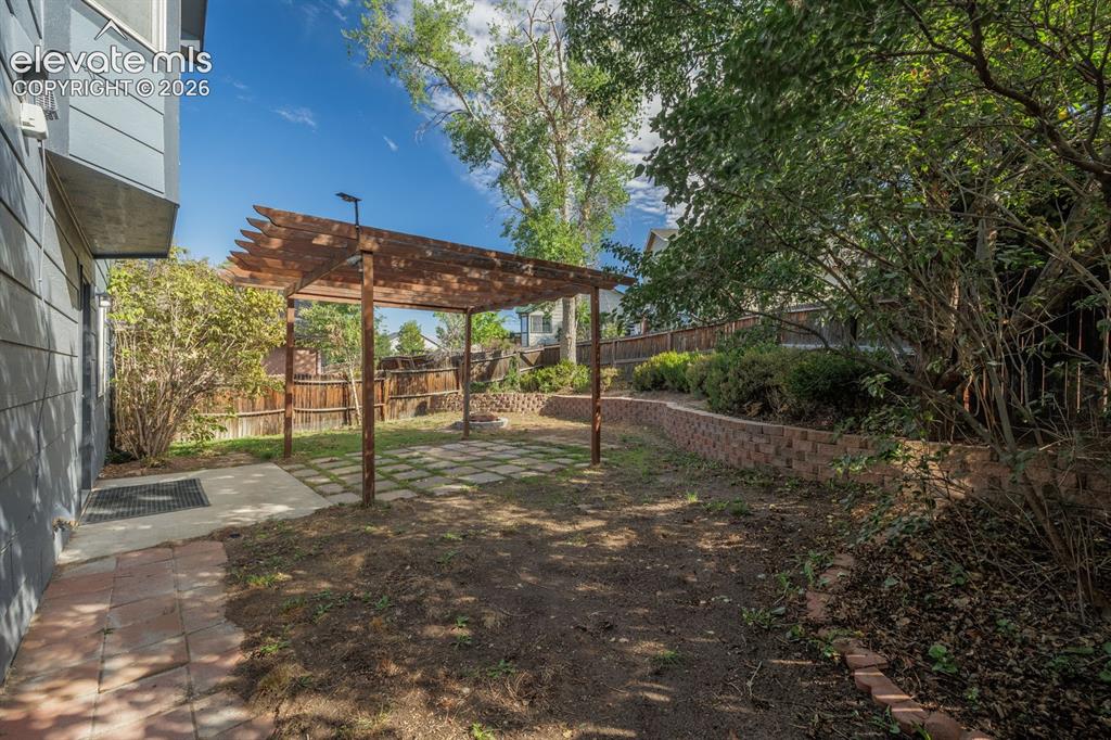 Image 29 of 36: Wood pergola over a patio area with square paver stones