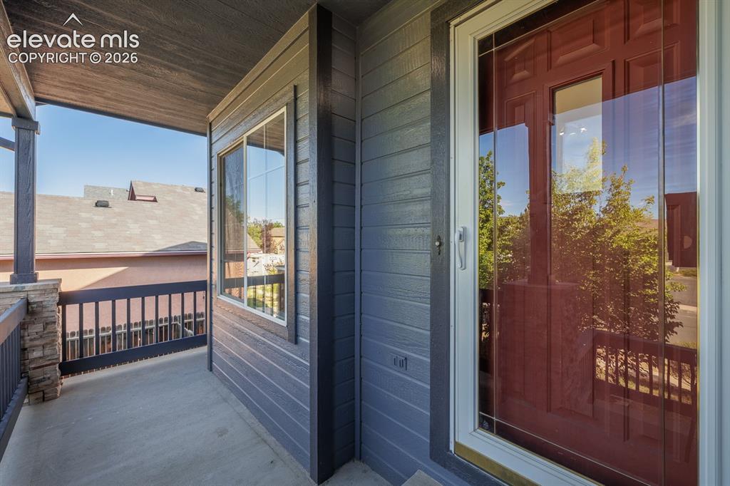 Image 3 of 36: Covered porch featuring a stone-clad column, dark wood railings, and textur