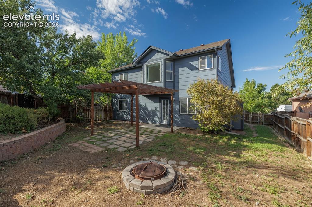 Image 31 of 36: Expansive backyard featuring a stone fire pit, a paver patio with a wood pe