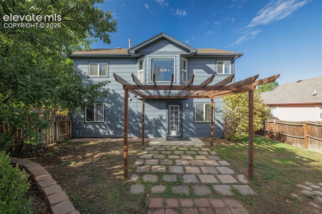 Image 32 of 36: Expansive backyard featuring a stone paver patio, a wood pergola structure,