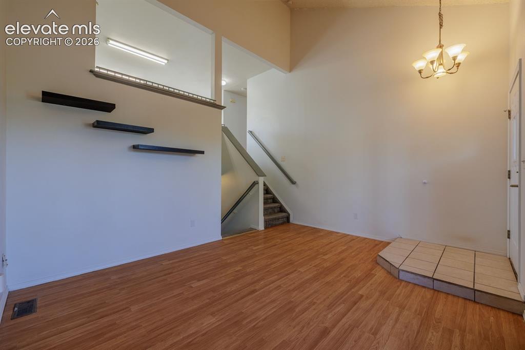 Image 5 of 36: Wood-finish flooring throughout, with a tiled entry landing, a chandelier f
