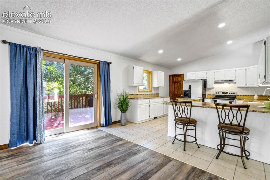 Image 11 of 45: Open-concept kitchen and living area featuring wood-finish flooring, white