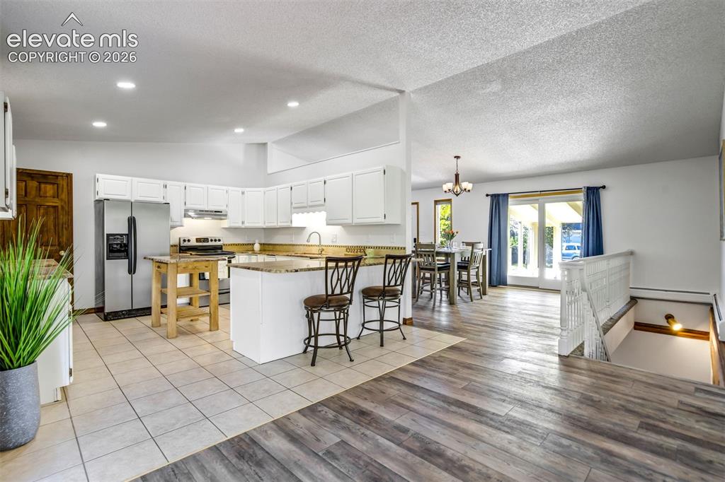 Image 12 of 45: Spacious open-concept kitchen featuring white cabinetry, stainless steel ap