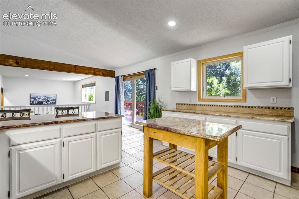 Image 14 of 45: Kitchen featuring white cabinetry, light-toned countertops, and tile floori