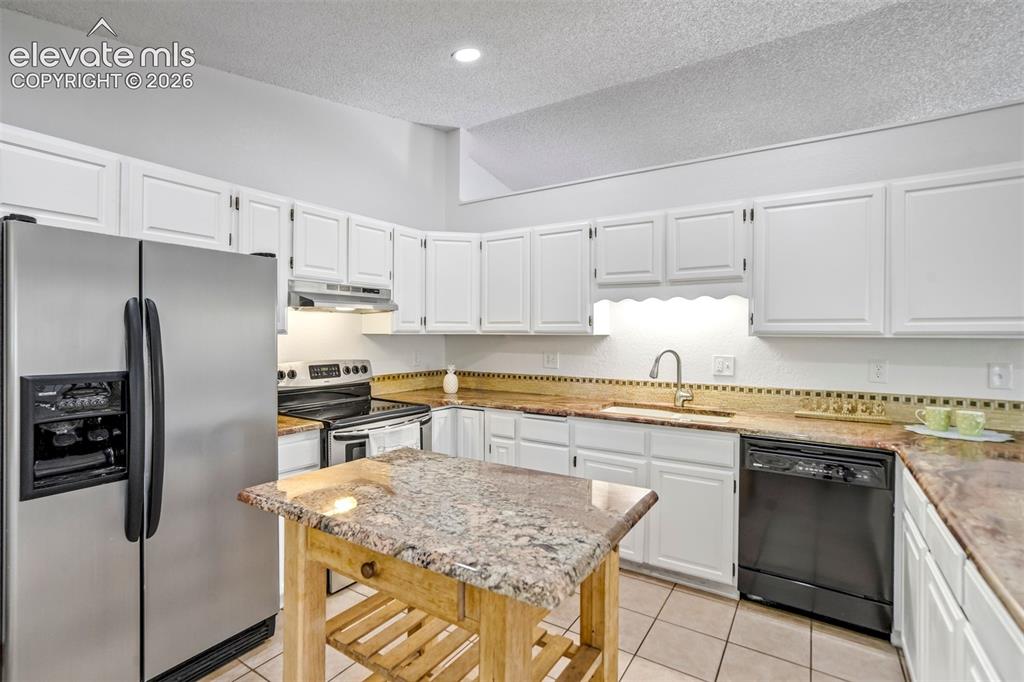 Image 15 of 45: Kitchen featuring white cabinetry, light-toned countertops, tile flooring,