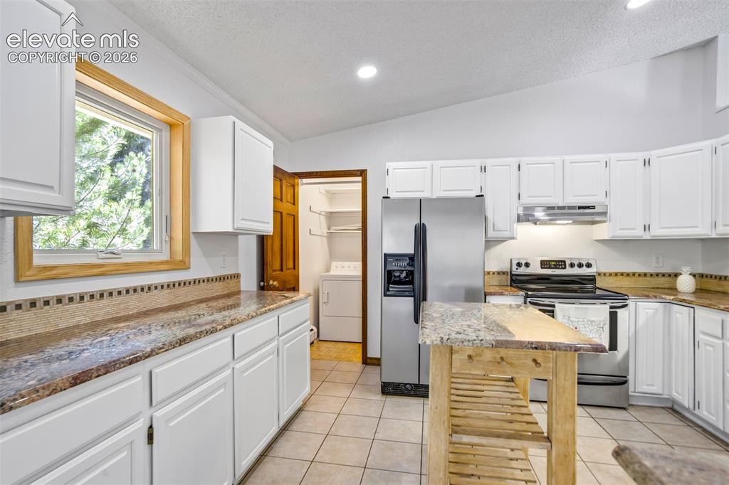 Image 16 of 45: Kitchen featuring white shaker cabinetry, speckled countertops, stainless s