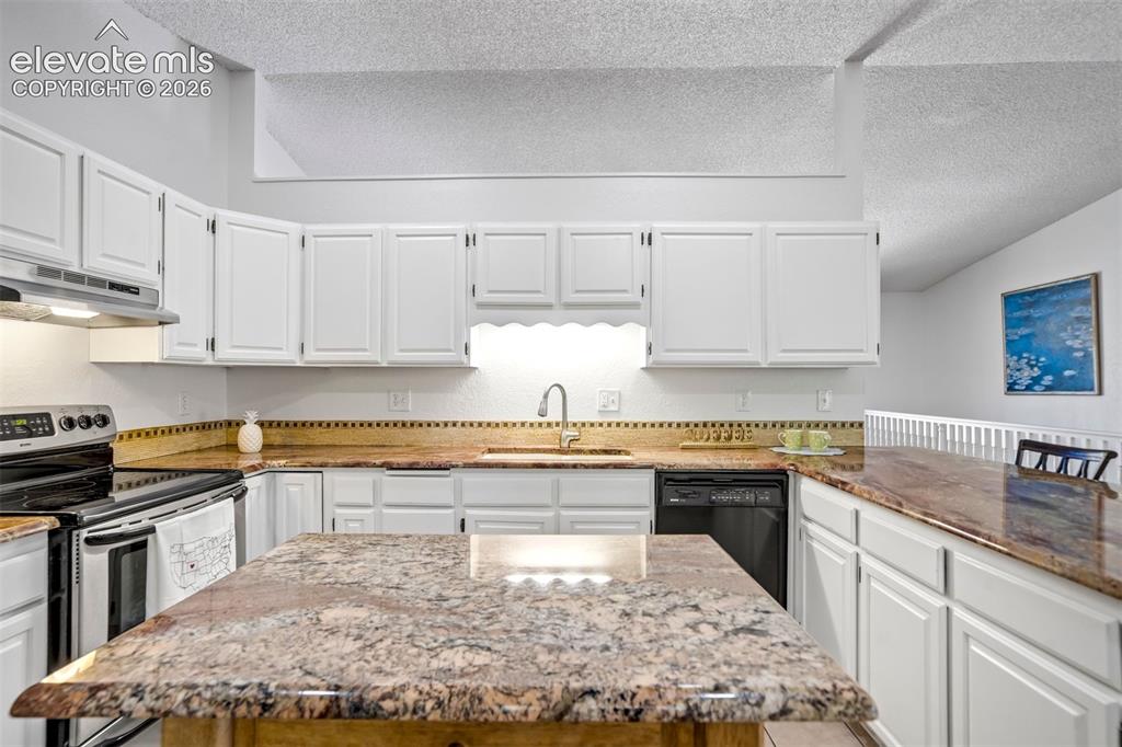 Image 17 of 45: Kitchen featuring white cabinetry, stone-finish countertops, tile backsplas