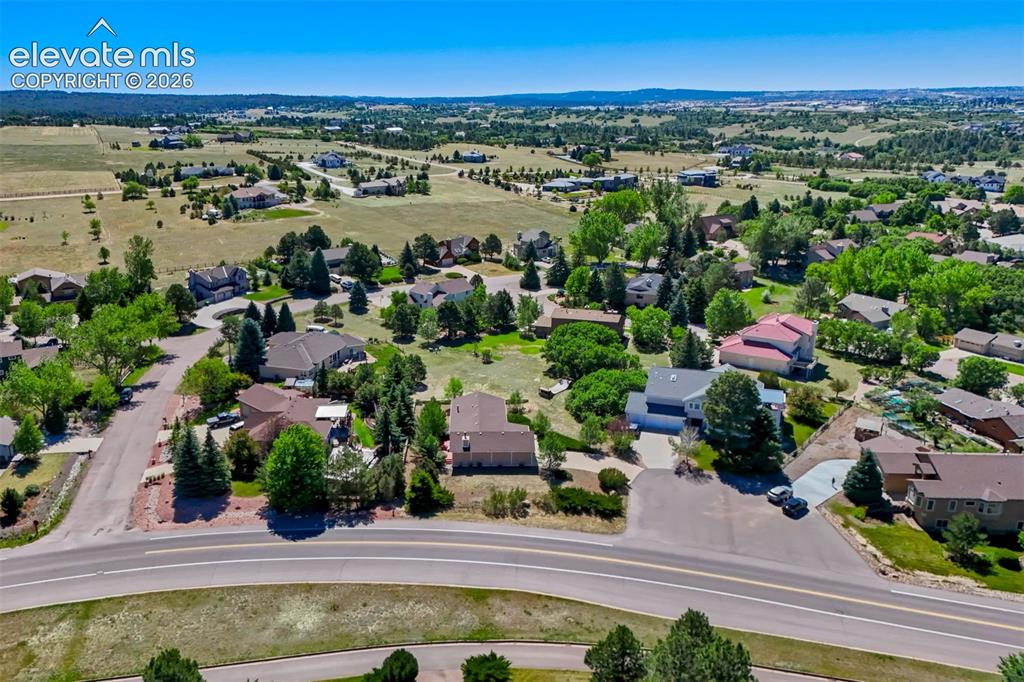 Image 45 of 45: Expansive aerial capturing a suburban landscape with a paved road and numer